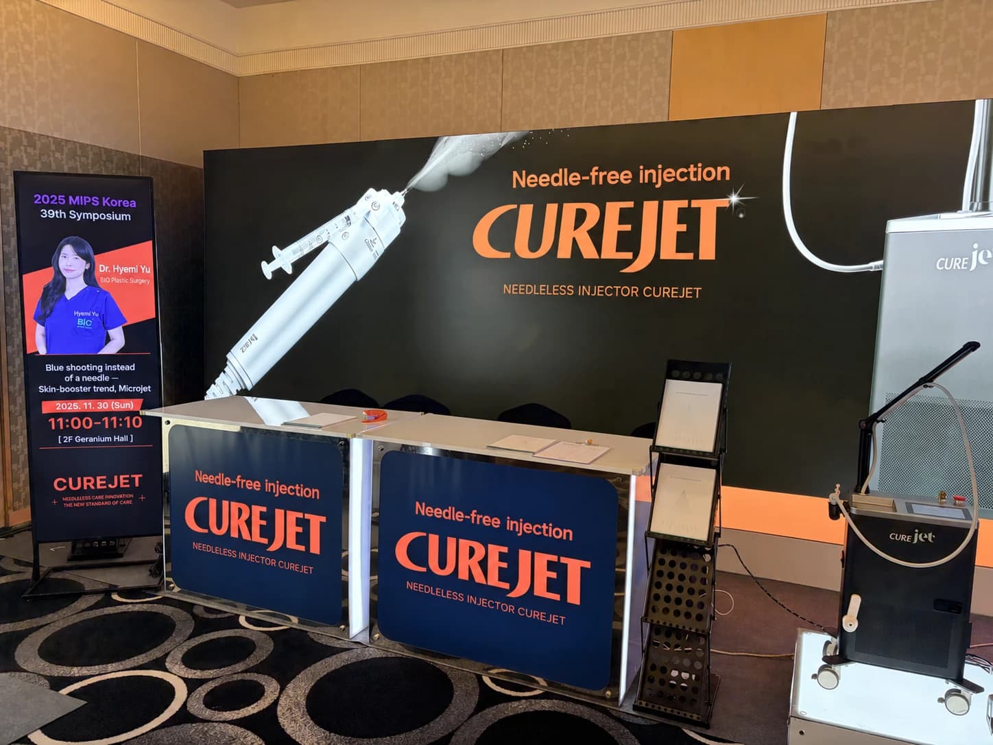 Conference device booth and speaker announcement — AI-assisted English text adaptation; not an unedited medical original