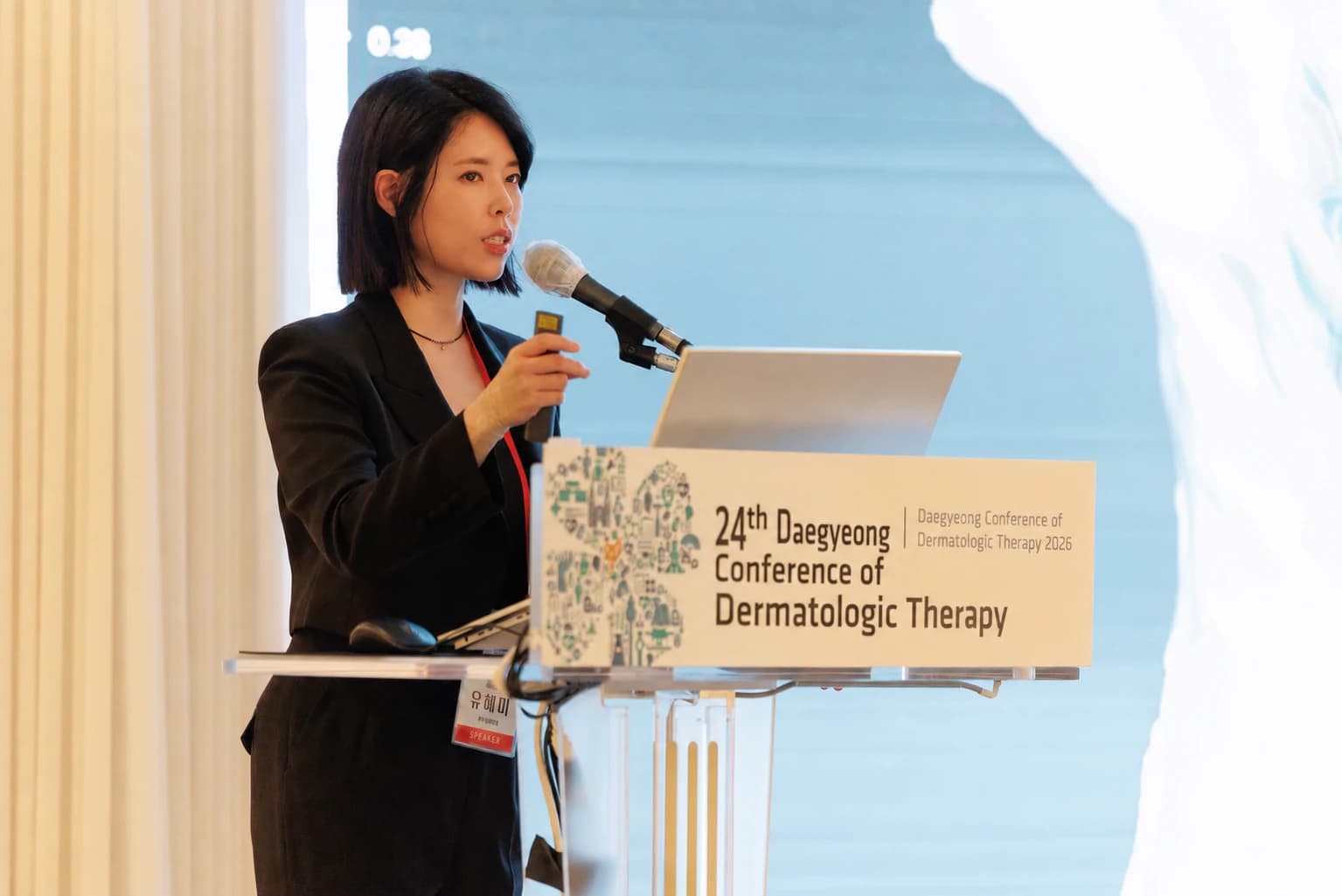 Dr. Hyemi Yu at an academic conference, with English podium lettering